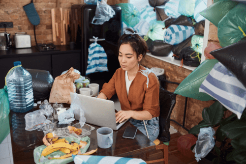 Hoarding A woman sitting at a computer surrounded by piles of garbage.
